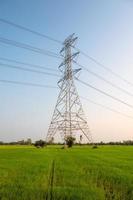 High voltage pole, Large transmission electric tower with cable on rice field with blue sky in countryside photo