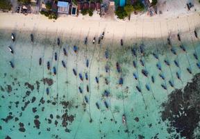 Wooden long-tail boat anchored on coastline in tropical sea photo