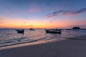 hermoso mar tropical con bote de madera en la mañana del amanecer foto