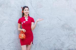 Asian beautiful girl in red dress stands holding a red bag among old city center Chinese new year theme. photo