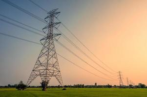 Arrangement of High voltage pole, Transmission tower on rice field at sunset photo