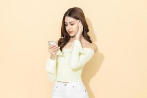 Portrait of serious concentrated attractive woman using mobile phone in hand on isolated pastel color background. typing message, design and advertising concept. photo