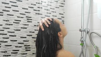 Young woman taking a shower and washing her hair in the bathroom photo