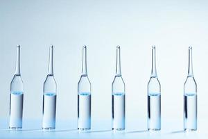 Six medicine ampules standing in a row. Blue monochrome medicine concept image. photo