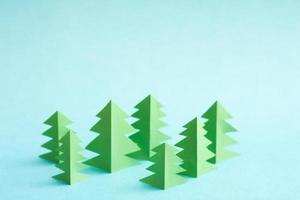 Green paper trees on blue background with free copy paste space. photo