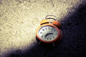 Vintage style orange alarm clock under the bright light and dark shadow. photo