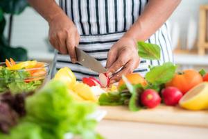 Vegetables and fruits such as mangos, lemons, bell peppers, tomatoes, carrots are prepared on the table and on a cutting board to cut, for salads in the kitchen.