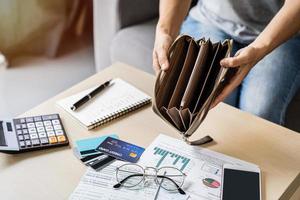 Stressed young woman open her empty wallet and calculating expenses at home photo