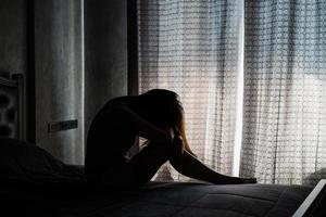 joven solitaria deprimida y estresada sentada en el dormitorio oscuro, concepto de emoción negativa foto