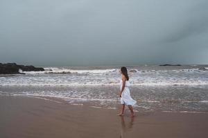 Young woman feeling lonely and sad looking at the sea on a gloomy day photo