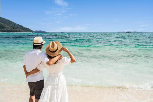 pareja joven viajera relajándose y disfrutando en la hermosa playa tropical de arena blanca con espuma de olas y mar transparente, vacaciones de verano y concepto de viaje foto