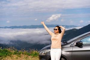 Young woman travelers with car watching a beautiful sea of fog over the mountain while travel driving road trip on vacation photo