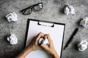 Hand holding crumpled paper balls with eye glasses and file folder on desk office, Creativity problems concept photo