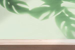 Empty wooden table with shadow of tropical green leave on color background with copy space photo