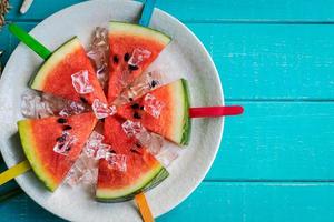 Watermelon slice popsicles with colorful stick on wooden background, Summer fruits photo