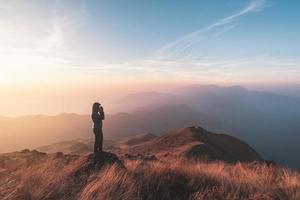 joven viajero mirando hermoso paisaje al atardecer en la montaña, concepto de estilo de vida de viaje de aventura foto