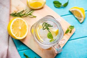 refrescante limonada en vaso con limón sobre mesa de madera foto