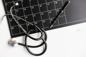 Stethoscope with calendar, medical appointment reminder and annual checkup concept, Top view photo