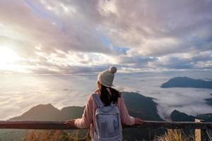Young woman travelers looking at the sunrise and the sea of mist on the mountain in the morning, Travel lifestyle concept photo