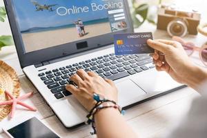 Young women planning summer vacation trip and searching information or booking hotel and using credit card on laptop, Travel concept photo