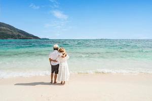 Young couple traveler relaxing and enjoying at beautiful tropical white sand beach with wave foam and transparent sea, Summer vacation and Travel concept photo