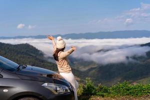 Young woman travelers with car watching a beautiful sea of fog over the mountain while travel driving road trip on vacation photo