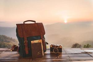 Travel backpack and retro camera with landscape view of mountain at sunrise photo