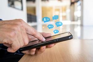 Close-up view of the cell phone in the hands of a man, person using a social media marketing concept on mobile phone with notification icons of like, message, comment and star above smartphone screen photo