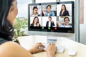 Back view of female employee speak talk on video call with colleagues on online event briefing, woman worker have Webcam group conference with coworkers on modern laptop at office photo