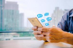 Close-up view of the cell phone in the hands of a man, person using a social media marketing concept on mobile phone with notification icons of like, message, comment and star above smartphone screen photo