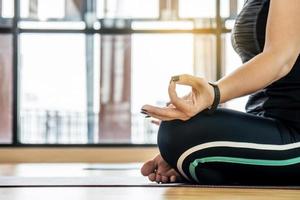 Attractive young woman exercising and sitting in yoga Lotus pose with mudra gesture position while resting at home, Concept of healthy life and natural balance between body and mental development photo