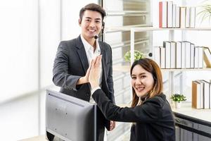 Business men and woman with headset as call center or business telesales on desk at the customer service office giving high five to be pleased with the success photo