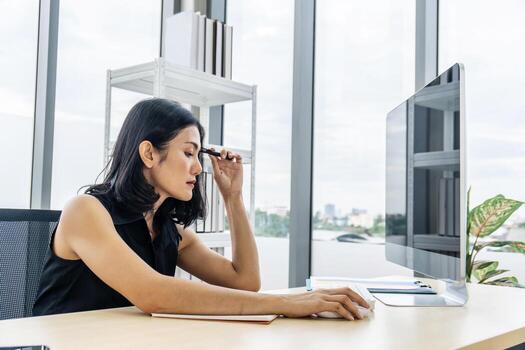 joven empresaria asiática profundamente pensada mientras trabajaba en una mesa en un edificio de oficinas moderno foto