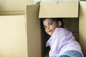 Relocating delivery services. Delivering happiness, African american cute baby girl enjoy playing with cardboard box at home, Insurance post package. Deliver your treasures. Storage for toys. photo