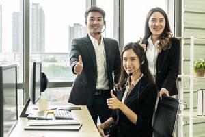 Handsome and Beautiful of call center or customer support operator smiling and showing thumbs up in headphones in office. Service mind concept photo