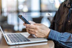Data Search Technology Search Engine Optimization. Man hands using smartphones searching for information in internet online society web with search box icon and working via laptop on table photo