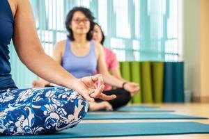 tiempo para el yoga. Atractiva mujer joven haciendo ejercicio y sentada en una pose de medio loto de yoga con posición de gesto de mudra mientras descansa en casa, bienestar, concepto de bienestar foto