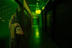 escena de terror de un misterioso y aterrador hombre negro sosteniendo una calavera en la mano en un espeluznante corredor de un edificio antiguo foto