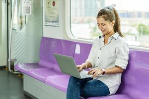 Beautiful woman working urgently on a laptop computer at the electric train in the morning