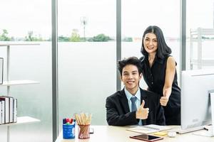 Joyful businessmen, Two businessman and woman sitting and standing at the table, Two business looking at the camera and showing thumb up photo