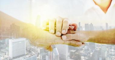 Double exposure Teamwork business join hand together concept, Image of shake hands and folding their hands on hands of success concept Symbol of cooperation in city background with copy space. photo