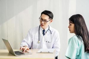 Doctor showing medical records on computer to his patient,he is pointing at the screen, Doctor explaining exam results in computer to patient at medical consultation, Medicine and health care concept photo