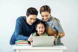 Happy young Asian family using at the laptop to surf internet together at home, , relaxing at home for lifestyle concept photo