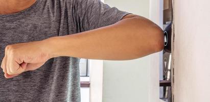 The young man uses an elbow to press the elevator button to prevent the spread of the Covit19 or corona virus photo