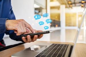 Close-up view of the cell phone in the hands of a man, person using a social media marketing concept on mobile phone with notification icons of like, message, comment and star above smartphone screen photo