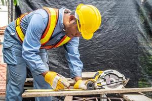 Construction worker are using tape measurements to measure planks and pencil are used to write, Male hands measuring wood flooring, Construction industry, housework do it yourself. photo