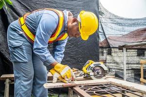 Construction worker wears protective leather gloves, with a pencil and the carpenter's square trace the cutting line on a wooden table. Construction industry, housework do it yourself. photo