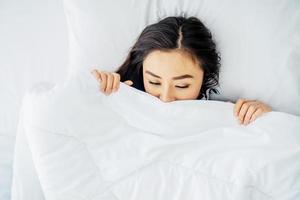 Top view of sleeping asian woman cover face with blanket flat lay. Close-up of young women, sleeping under white blanket and covering half face. Copy space for advertisement photo
