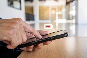 Businessman holding a phone with a low battery charge screen While working on table, I need to find a quick charger photo