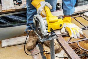 carpintero que usa sierra circular para cortar tablas de madera con herramientas eléctricas, construcción y renovación de viviendas, herramientas de reparación y construcción foto